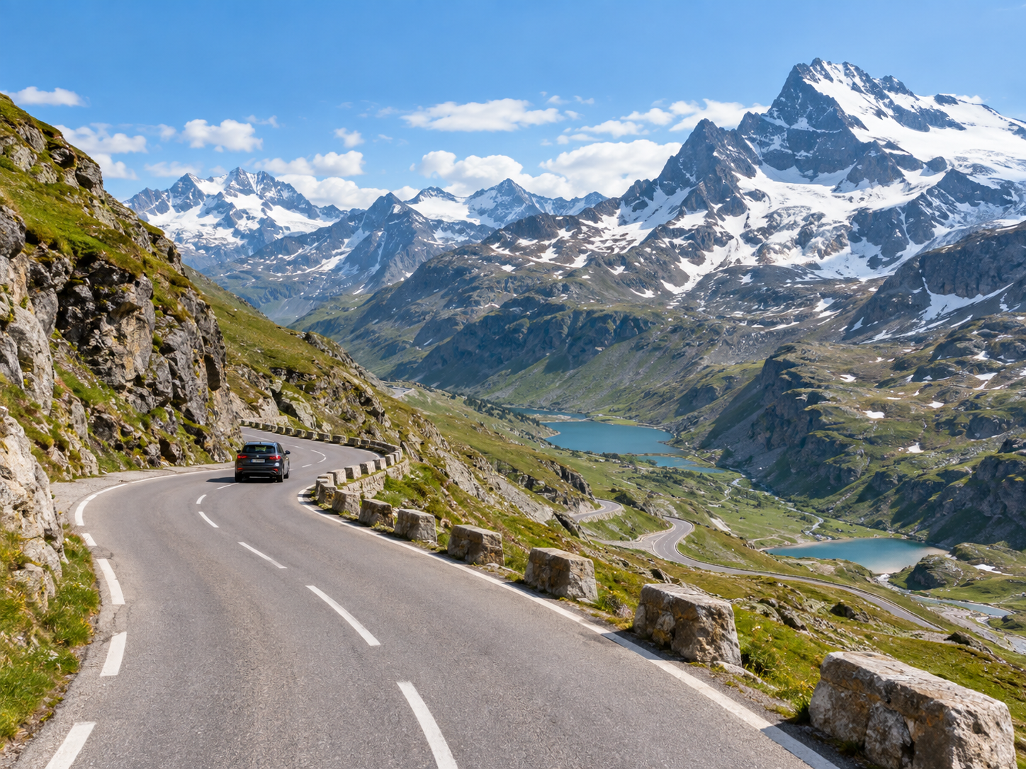 Mountain road winding through the French Alps with lakes and snowy peaks