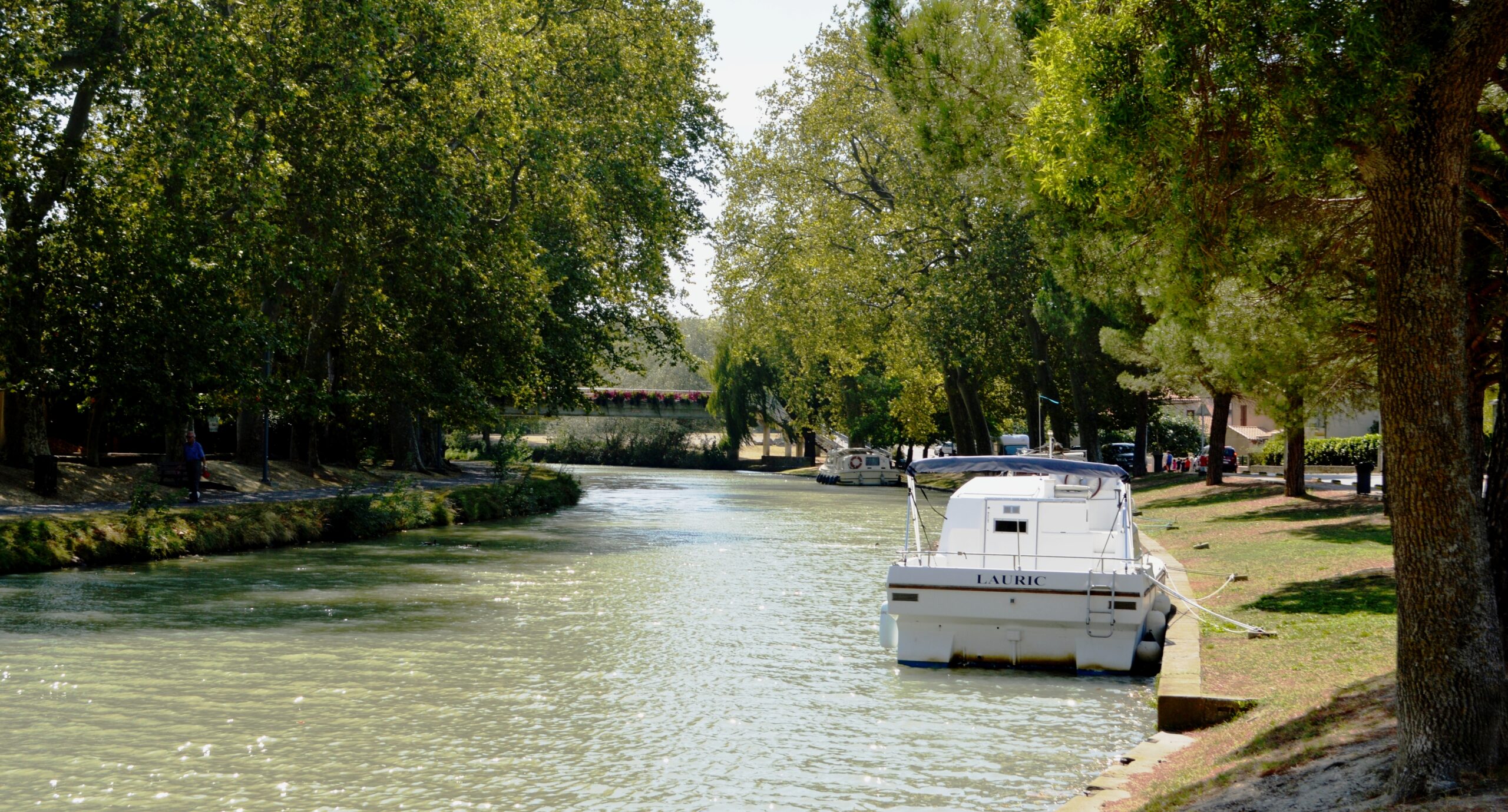 Boats on a tree-lined stretch of the Canal du Midi near Castelnaudary